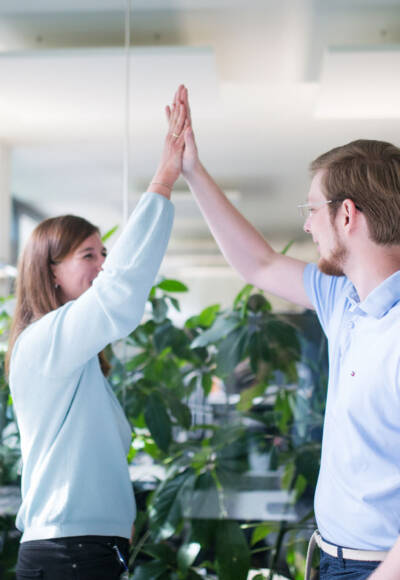 Zwei IT-Experten freuen sich über eine gelungene Teamarbeit und geben sich ein Highfive.