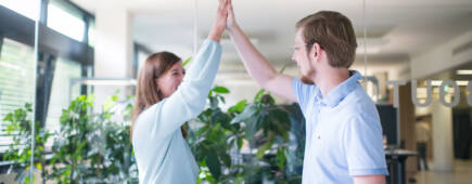 Zwei IT-Experten freuen sich über eine gelungene Teamarbeit und geben sich ein Highfive.