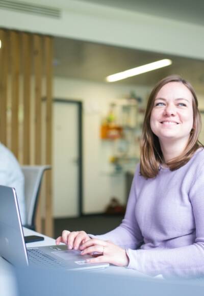 Frau sitzt im Büro am Arbeitsplatz und lächelt